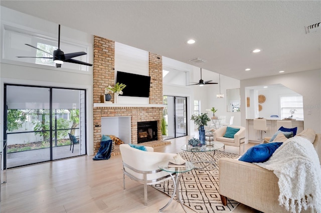 living room with ceiling fan, a fireplace, lofted ceiling, and light hardwood / wood-style flooring