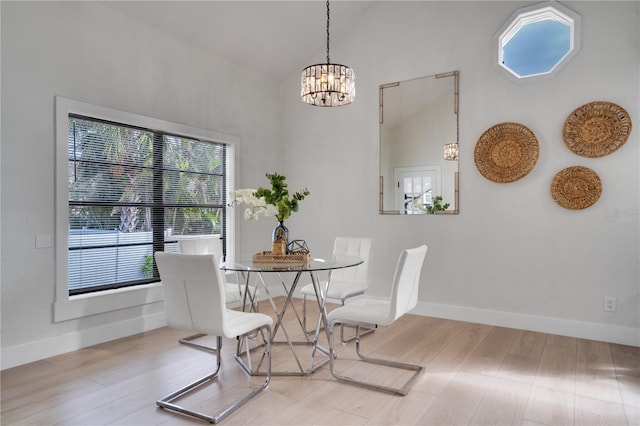 dining room featuring hardwood / wood-style flooring, a notable chandelier, and high vaulted ceiling