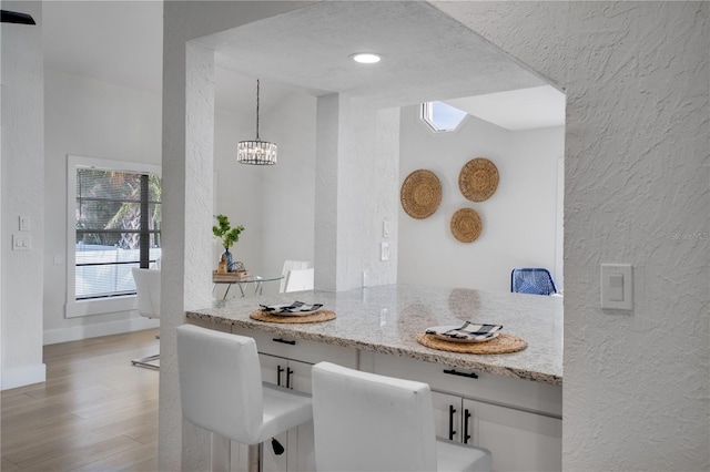 interior space with a chandelier, a textured ceiling, and light hardwood / wood-style flooring