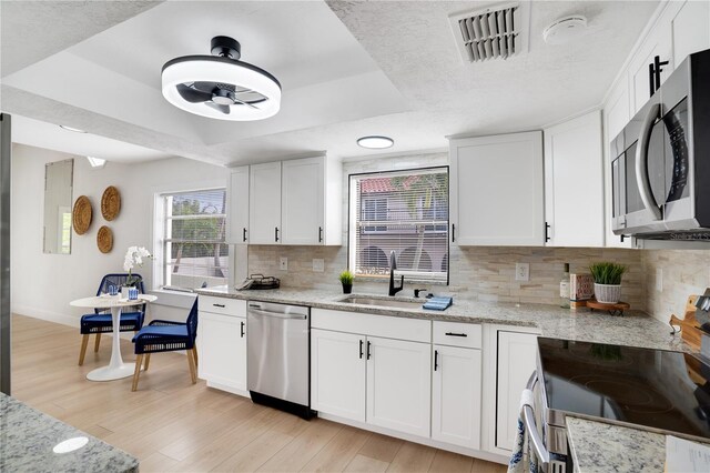 kitchen with light hardwood / wood-style floors, sink, white cabinetry, and stainless steel appliances