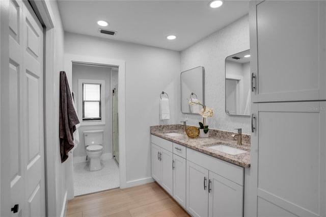 bathroom featuring hardwood / wood-style flooring, vanity, toilet, and a shower with door