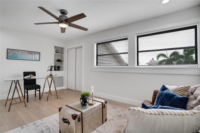 living room featuring ceiling fan, built in features, and light wood-type flooring