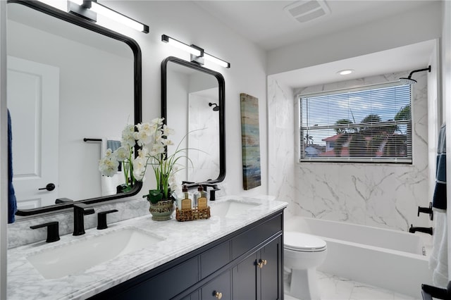 full bathroom featuring vanity, tiled shower / bath combo, and toilet