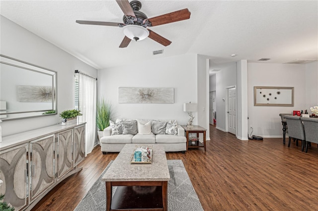 living room with a textured ceiling, dark hardwood / wood-style flooring, and ceiling fan