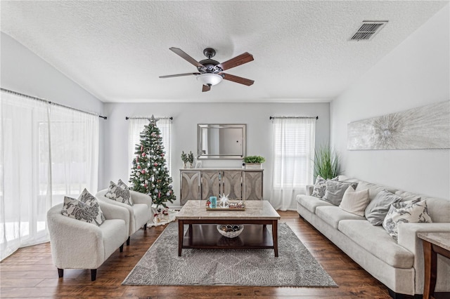 living room with a textured ceiling, dark hardwood / wood-style flooring, vaulted ceiling, and ceiling fan