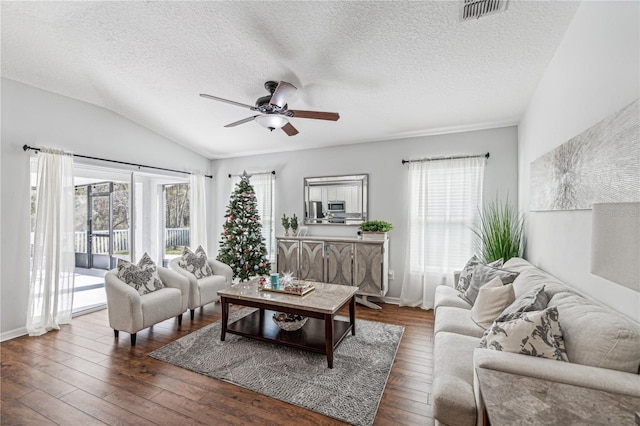 living room with a textured ceiling, ceiling fan, dark wood-type flooring, and vaulted ceiling