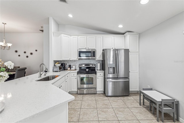 kitchen with sink, hanging light fixtures, vaulted ceiling, white cabinets, and appliances with stainless steel finishes