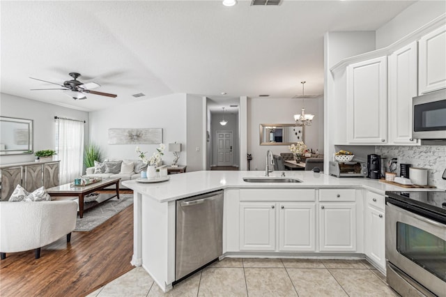 kitchen featuring white cabinetry, sink, stainless steel appliances, kitchen peninsula, and vaulted ceiling