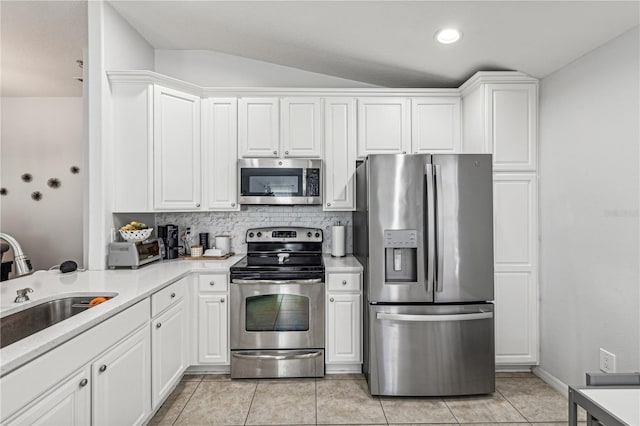 kitchen with appliances with stainless steel finishes, white cabinetry, and lofted ceiling