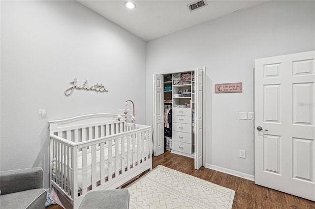 bedroom featuring dark hardwood / wood-style flooring and a nursery area