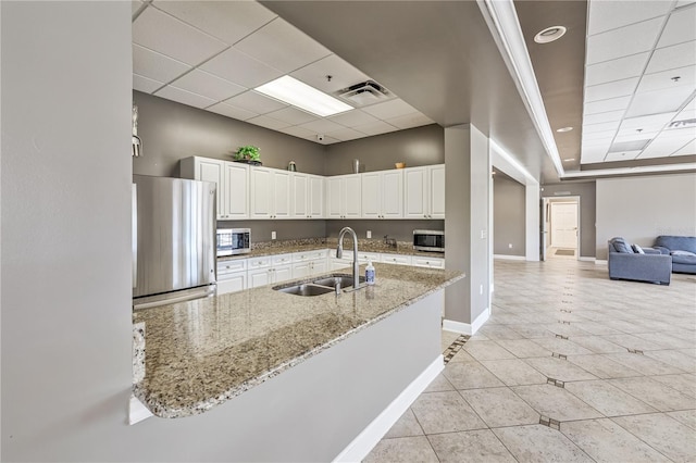 kitchen with light stone countertops, sink, a drop ceiling, stainless steel appliances, and white cabinets