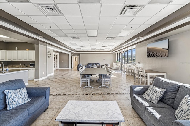 living room featuring a paneled ceiling, light tile patterned floors, and sink