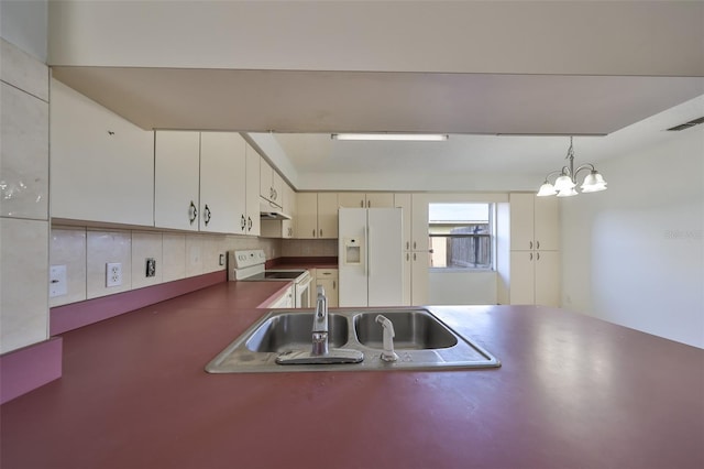 kitchen featuring backsplash, white appliances, sink, pendant lighting, and an inviting chandelier