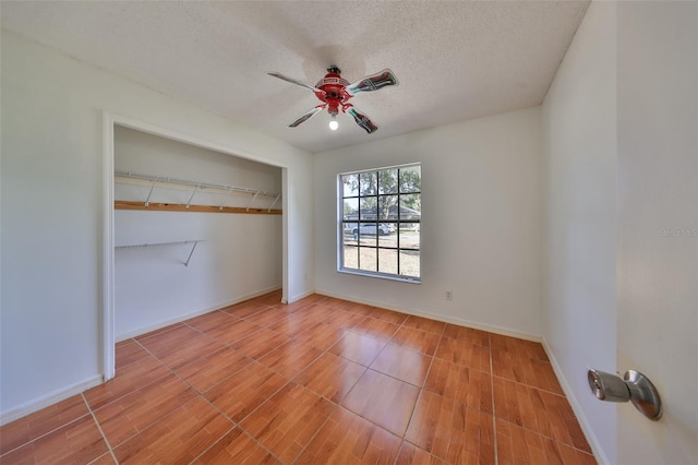 unfurnished bedroom featuring ceiling fan, a textured ceiling, and a closet