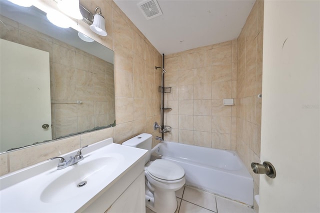 full bathroom featuring tiled shower / bath combo, tile patterned flooring, toilet, vanity, and tile walls