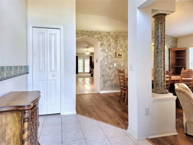 hall with tile patterned flooring, lofted ceiling, and ornate columns