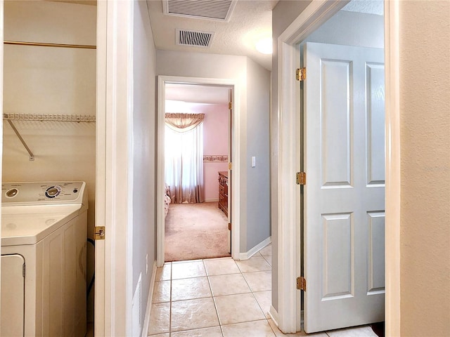 clothes washing area with light colored carpet, a textured ceiling, and washer / clothes dryer