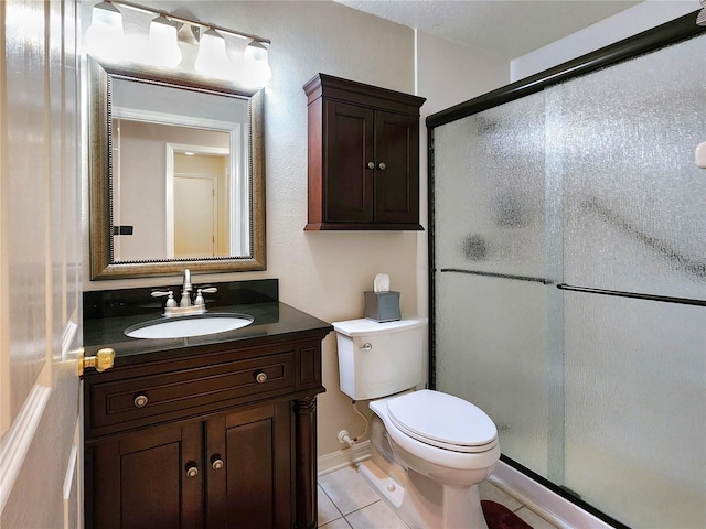 bathroom featuring tile patterned flooring, vanity, toilet, and walk in shower