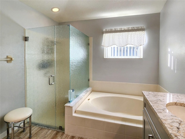 bathroom featuring plus walk in shower, vanity, and hardwood / wood-style flooring