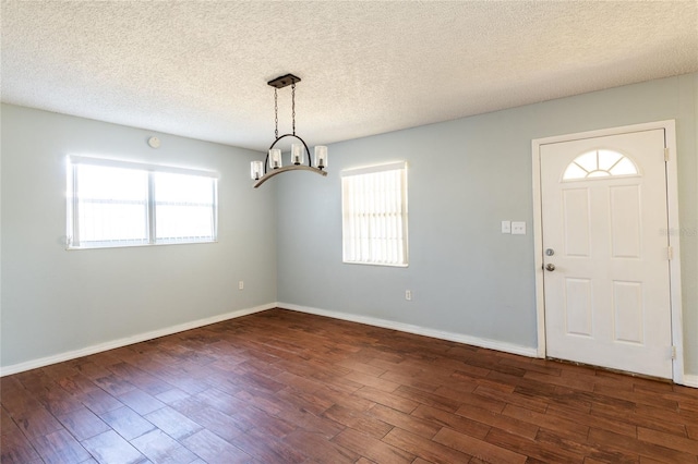 entrance foyer with a notable chandelier, dark hardwood / wood-style floors, and a textured ceiling