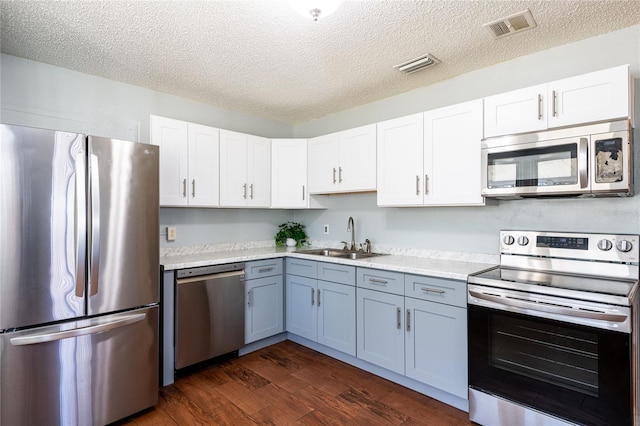 kitchen featuring sink, stainless steel appliances, dark hardwood / wood-style flooring, a textured ceiling, and white cabinets