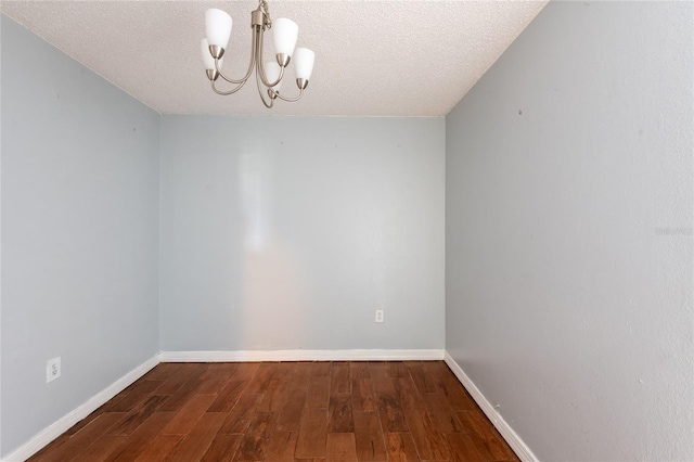 empty room with hardwood / wood-style floors, a textured ceiling, and an inviting chandelier