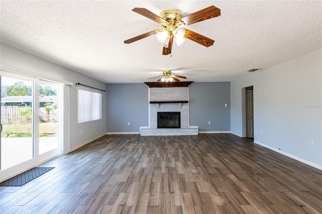 unfurnished living room with a fireplace, a textured ceiling, dark hardwood / wood-style flooring, and a healthy amount of sunlight