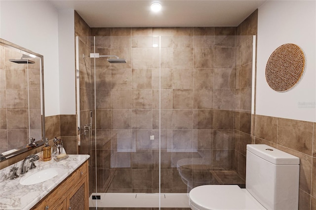 bathroom featuring an enclosed shower, vanity, toilet, and tile walls