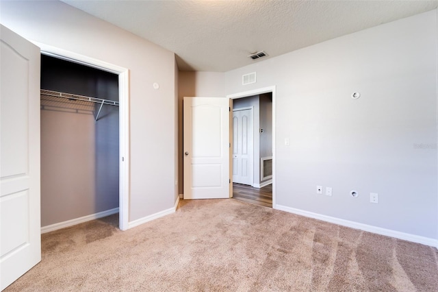 unfurnished bedroom with a textured ceiling, carpet floors, and a closet