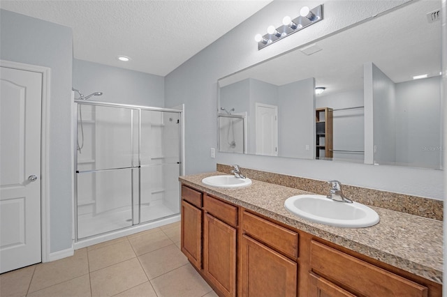 bathroom with tile patterned flooring, vanity, a shower with door, and a textured ceiling