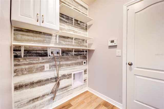 laundry area featuring electric dryer hookup, cabinets, hookup for a washing machine, and light hardwood / wood-style floors