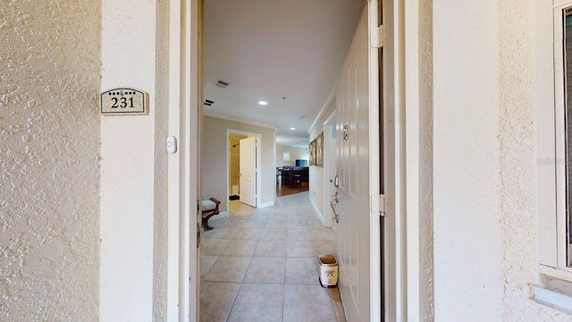 hall with light tile patterned floors and ornamental molding