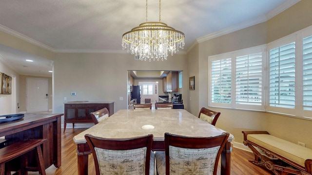 dining room with light hardwood / wood-style floors, an inviting chandelier, and crown molding