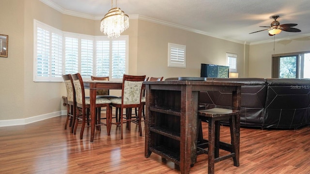 dining room with ceiling fan with notable chandelier, hardwood / wood-style flooring, a wealth of natural light, and crown molding