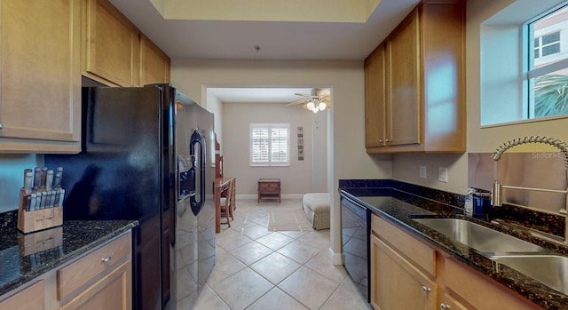 kitchen with dark stone countertops, sink, light tile patterned flooring, and black appliances