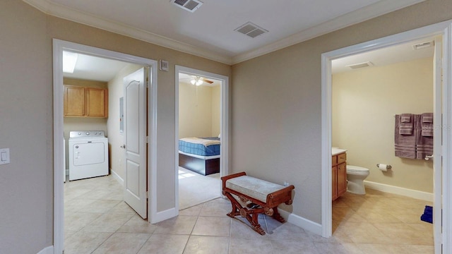 corridor with washer / clothes dryer, crown molding, and light tile patterned floors