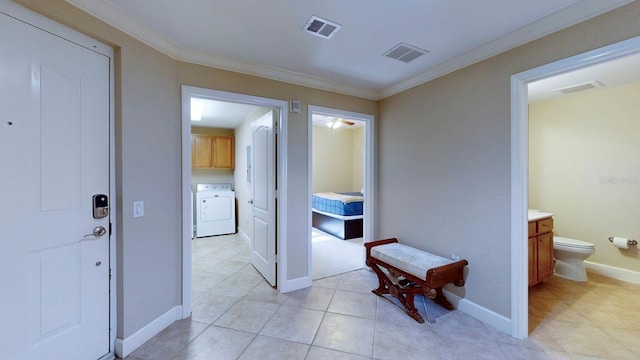 hallway featuring crown molding, light tile patterned floors, and washer / dryer