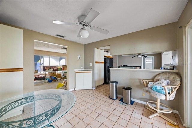 kitchen with ceiling fan, black fridge, and light tile patterned floors