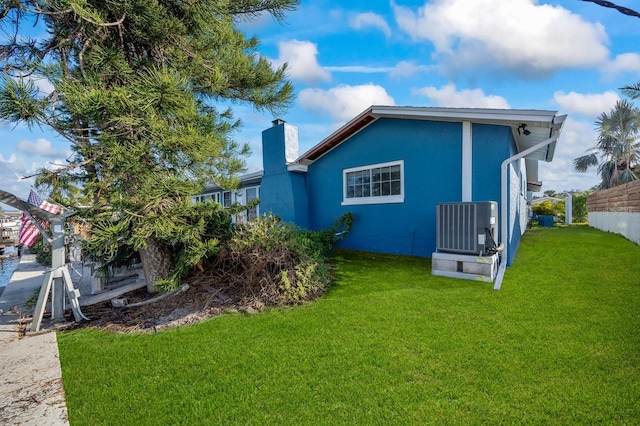 back of property featuring a lawn and central AC