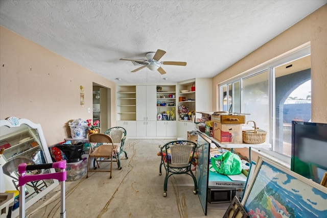 interior space featuring built in shelves, ceiling fan, and a textured ceiling