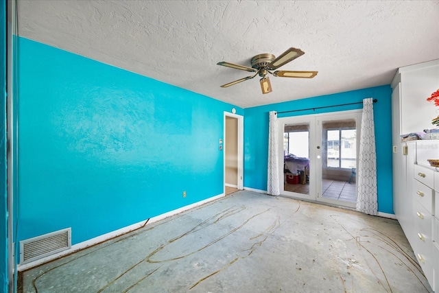 empty room with ceiling fan, a textured ceiling, and french doors