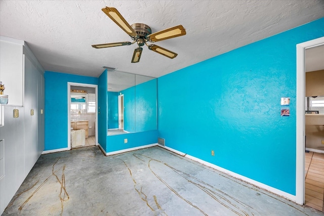 spare room featuring ceiling fan, concrete flooring, and a textured ceiling