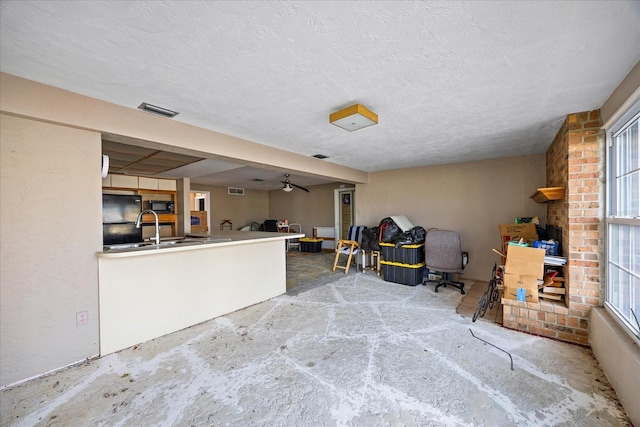 interior space with a wealth of natural light, black refrigerator, sink, and a textured ceiling