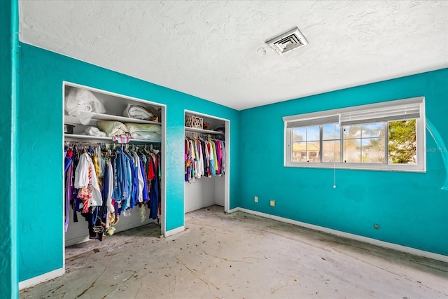 unfurnished bedroom featuring a textured ceiling and two closets