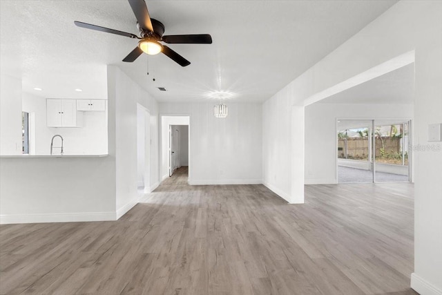 unfurnished living room featuring sink, light hardwood / wood-style floors, and ceiling fan