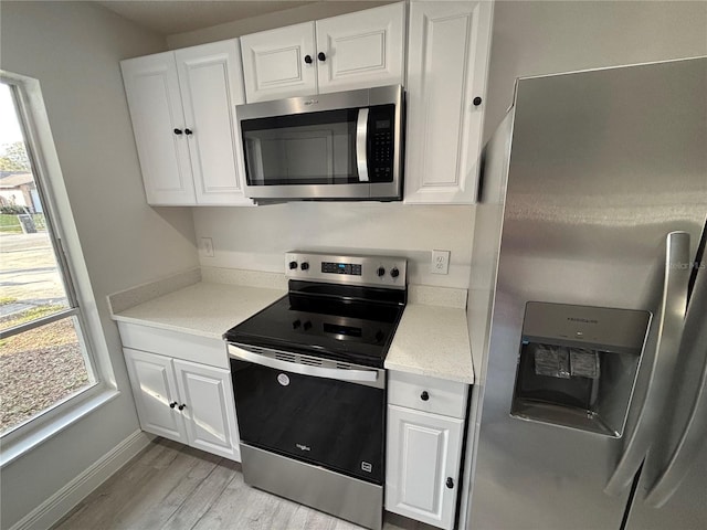 kitchen featuring white cabinetry, light stone countertops, light hardwood / wood-style flooring, and stainless steel appliances