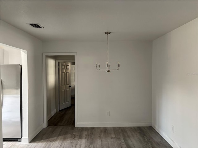 unfurnished dining area featuring hardwood / wood-style flooring and an inviting chandelier