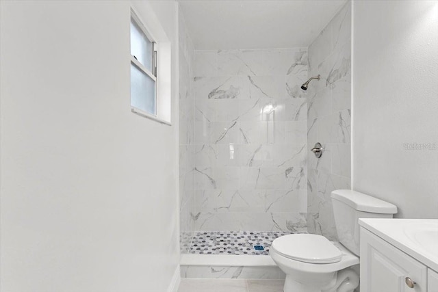 bathroom featuring vanity, a tile shower, and toilet