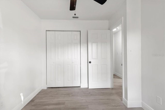 unfurnished bedroom with ceiling fan, a closet, and light wood-type flooring