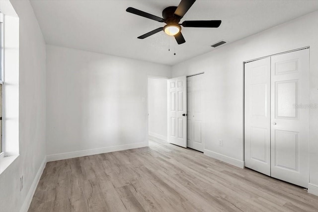 unfurnished bedroom with multiple closets, ceiling fan, and light hardwood / wood-style floors